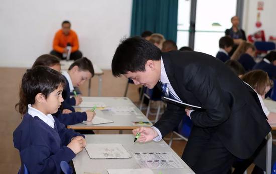  中国数学教师为伦敦一所小学学生批改课堂练习题。新华社记者韩岩 摄